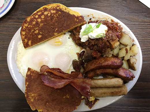 The Cowboyâ€™s Breakfast ($12) -- Three eggs, smoked bacon, sausage, grilled chorizo and chili smothered hashbrowns. Served with corn cakes. Chuckwagon not included.